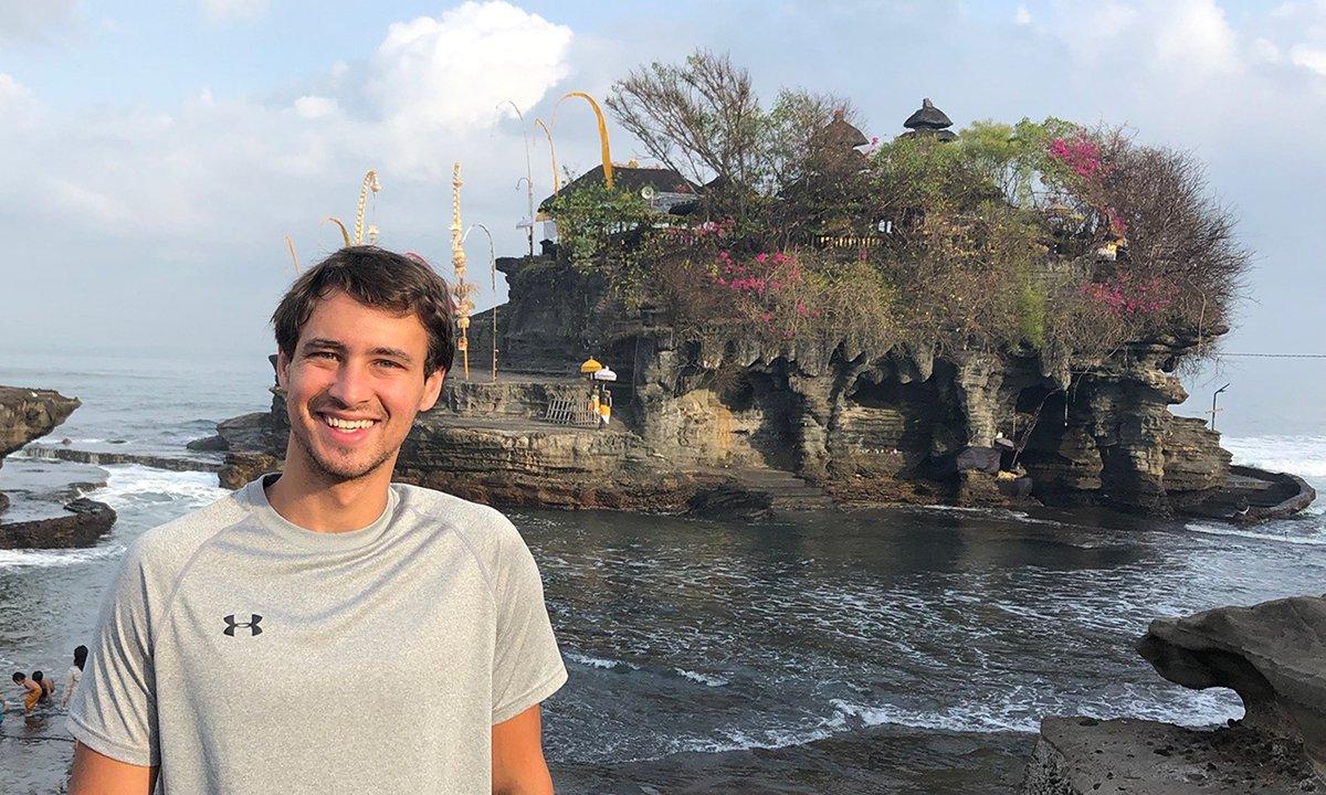 A man posing in front of a scenic island background